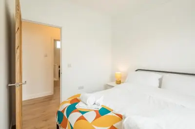 a bedroom with a large bed and a mirror at Cosy Two Bedroom Apartment in Excellent Location in Chesterton