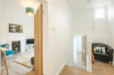 a living room with a black couch and a chair at Cosy Two Bedroom Apartment in Excellent Location in Chesterton