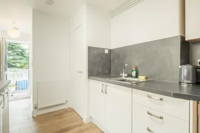 a kitchen with white cabinets and a sink at Cosy Two Bedroom Apartment in Excellent Location in Chesterton