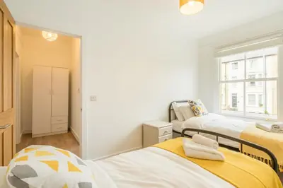 a bedroom with three beds and a window at Cosy Two Bedroom Apartment in Excellent Location in Chesterton
