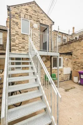 a staircase leading to a house with a basketball hoop at Cosy Two Bedroom Apartment in Excellent Location in Chesterton