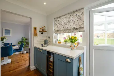 a kitchen with a blue cabinet and a window at 2 Hillcrest - Aldeburgh Coastal Cottages in Leiston