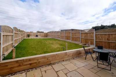 a patio with a yard with a table and chairs at 2 Hillcrest - Aldeburgh Coastal Cottages in Leiston