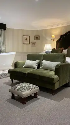 a living room with a green couch and a bed at Worlington Hall in Worlington