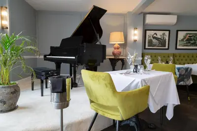 a dining room with a piano and a table and chairs at Worlington Hall in Worlington