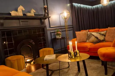 a living room with a couch and a fireplace with two candles at Worlington Hall in Worlington
