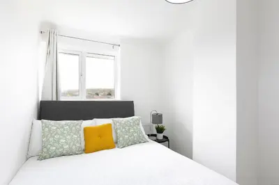a white bedroom with a white bed and a window at Skyvillion - STEVENAGE SPACIOUS & COZY 3Bed House with Parking, Wifi, Garden in Aston End
