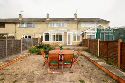 a patio with a table and chairs in front of a house at Skyvillion - STEVENAGE SPACIOUS & COZY 3Bed House with Parking, Wifi, Garden in Aston End