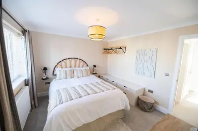 a bedroom with a large bed and a window at La Casita - Inside the Gates of Frinton-On-Sea in Frinton-on-Sea