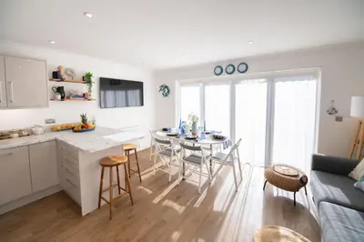 a kitchen and living room with a table and chairs at La Casita - Inside the Gates of Frinton-On-Sea in Frinton-on-Sea