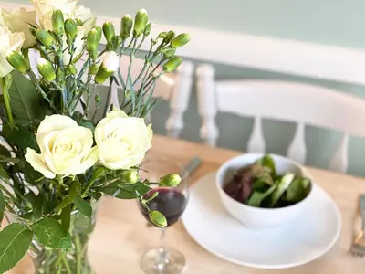 a table with a vase of roses and a bowl of vegetables at 6 Coastguard Cottages, Aldeburgh in Aldeburgh