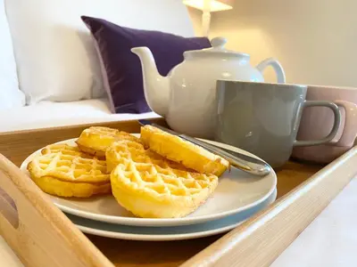 a white plate with waffles and a cup of tea at 6 Coastguard Cottages, Aldeburgh in Aldeburgh
