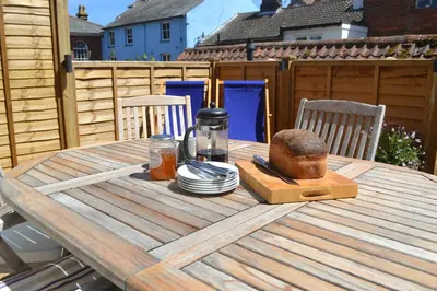 a wooden table with a cutting board on top of it at 6 Coastguard Cottages, Aldeburgh in Aldeburgh