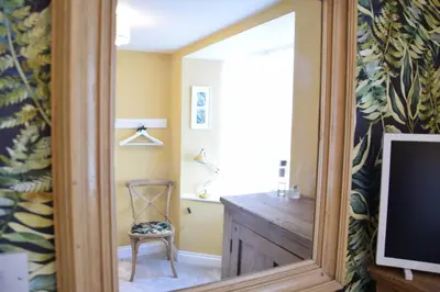 a mirror in a room with a chair and a television at Cragside, Aldeburgh in Aldeburgh