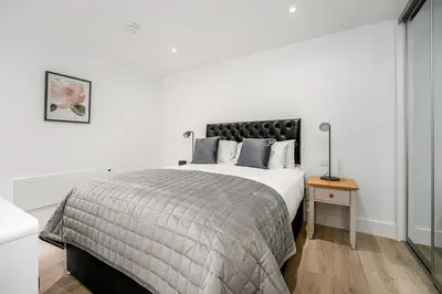 a white bedroom with a large bed and a table at Citystay Living - Finch House in Cambridge