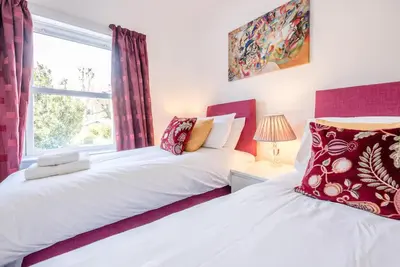 two beds in a bedroom with a window at Cornerstone, Aldeburgh in Aldeburgh