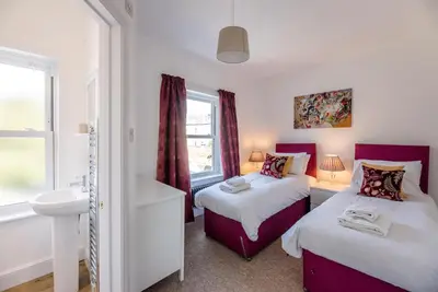 a bedroom with two beds and a sink and a window at Cornerstone, Aldeburgh in Aldeburgh