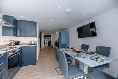 a kitchen with blue cabinets and a table and chairs at Cornerstone, Aldeburgh in Aldeburgh