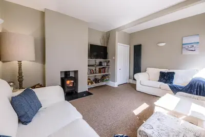 a living room with two white couches and a fireplace at Cornerstone, Aldeburgh in Aldeburgh