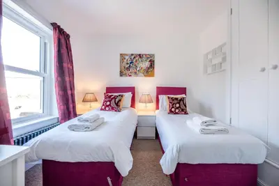 two twin beds in a room with a window at Cornerstone, Aldeburgh in Aldeburgh