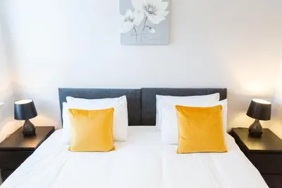 a bedroom with a white bed with two yellow pillows at Velvet 2-bedroom apartment, Brewery Road, Hoddesdon in Hoddesdon
