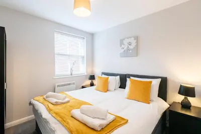 a bedroom with a large white bed with yellow pillows at Velvet 2-bedroom apartment, Brewery Road, Hoddesdon in Hoddesdon