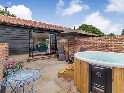 a hot tub on the patio of a house at The Old Workshop in Gipping