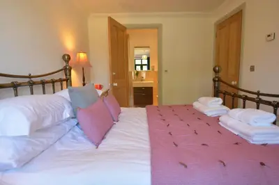 a bedroom with a large bed with white sheets and pink pillows at Badminton, Thorpeness in Thorpeness