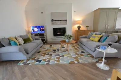 a living room with two couches and a tv at Badminton, Thorpeness in Thorpeness