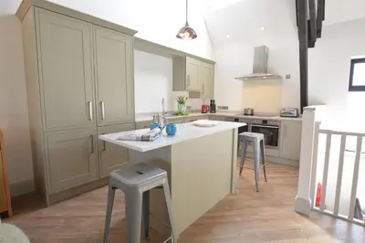 a kitchen with a white counter and stools in it at Badminton, Thorpeness in Thorpeness