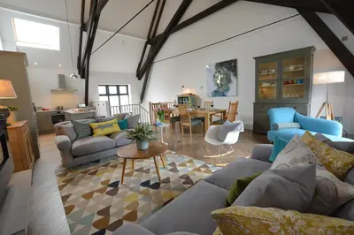 a living room with couches and a dining room at Badminton, Thorpeness in Thorpeness