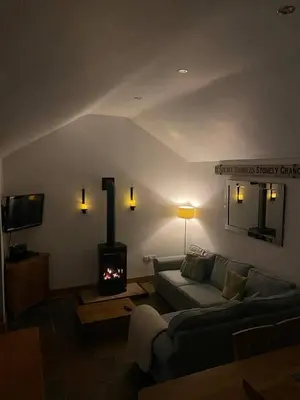 a living room with a couch and a wood stove at The Knox - Beautiful Two Bed Cottage Near Orford in Woodbridge