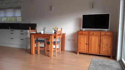a kitchen with a table and a television on a cabinet at The Annexe, Cornfields in Elmswell