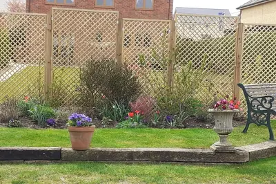 a garden with a bench and flowers and a fence at The Annexe, Cornfields in Elmswell