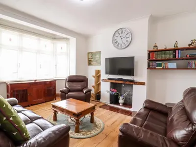 a living room with leather furniture and a clock on the wall at Ninety Eight in Southend-on-Sea