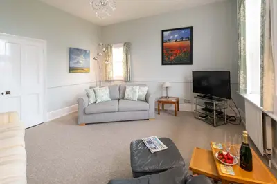 a living room with a couch and a tv at 4 Crespigny House - Aldeburgh Coastal Cottages in Aldeburgh