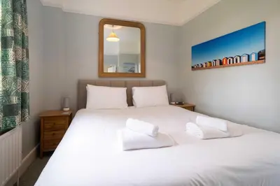 a bedroom with a white bed and a mirror at 4 Crespigny House - Aldeburgh Coastal Cottages in Aldeburgh