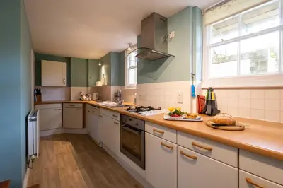 a kitchen with green and white cabinets and a counter top at 4 Crespigny House - Aldeburgh Coastal Cottages in Aldeburgh