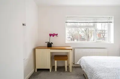 a bedroom with a table with a flower on it at Stevenage Contractors x8 New 3 bedroom House Free Wifi, Parking, Towels all inclusive & Large Garden in Stevenage