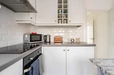 a white kitchen with white cabinets and a microwave at Stevenage Contractors x8 New 3 bedroom House Free Wifi, Parking, Towels all inclusive & Large Garden in Stevenage