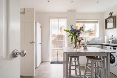 a kitchen with a table with a vase of flowers on it at Stevenage Contractors x8 New 3 bedroom House Free Wifi, Parking, Towels all inclusive & Large Garden in Stevenage