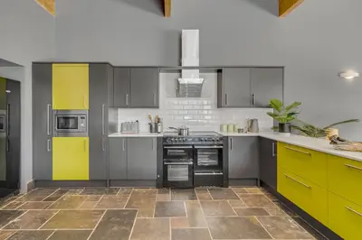 a kitchen with gray cabinets and yellow accents at 4 Bedroom House in Larling, near Thetford in Snetterton