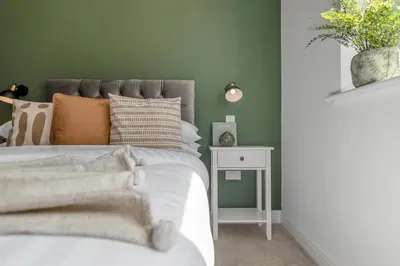 a bedroom with green walls and a bed with white sheets at 4 Bedroom House in Larling, near Thetford in Snetterton