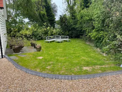 a garden with a bench in the grass at Debussys Guest House in Saffron Walden
