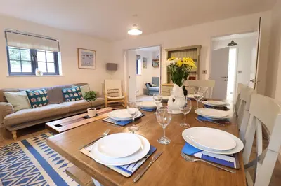 a dining room and living room with a wooden table at Corner Cottage, Thorpeness in Thorpeness