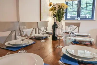 a dining room table with a bottle of wine and glasses at Corner Cottage, Thorpeness in Thorpeness