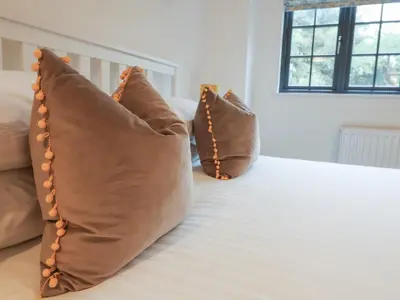 two brown pillows sitting on a bed at Corner Cottage, Thorpeness in Thorpeness