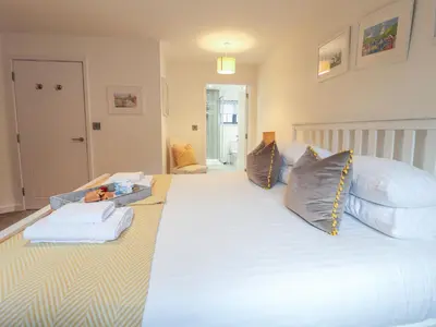 a large white bed with a baby on it at Corner Cottage, Thorpeness in Thorpeness