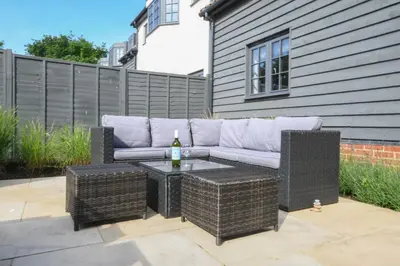a patio with a couch and a table with a bottle of wine at Corner Cottage, Thorpeness in Thorpeness