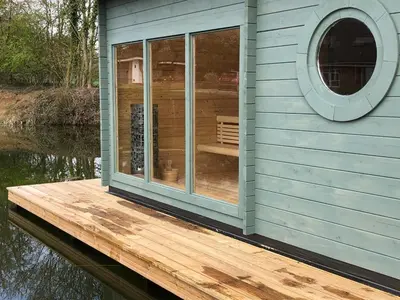 a house on a dock on a body of water at The Tawny Shepherd Hut, Whitehouse Farm in Stowmarket